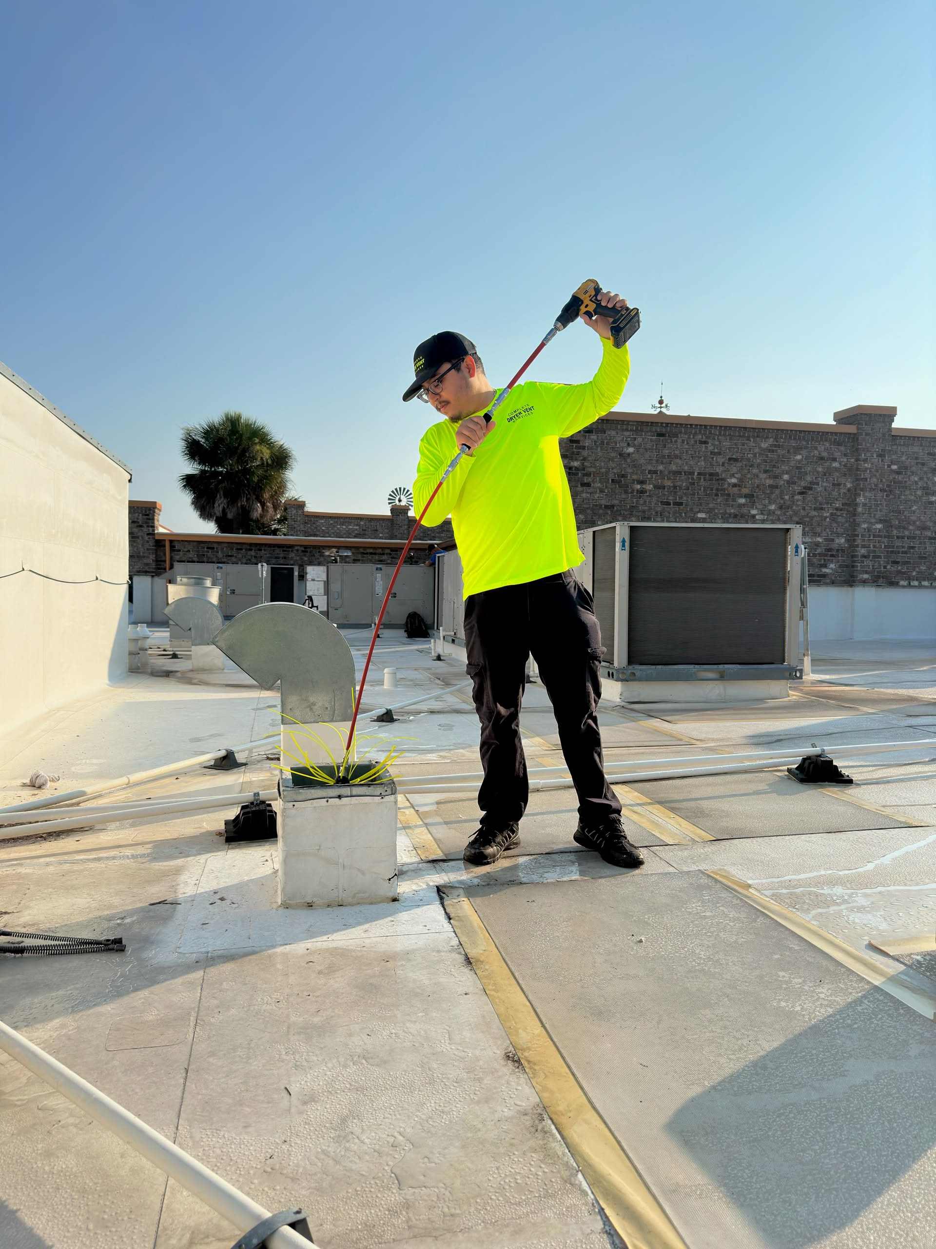 Dryer Vent Cleaning in Ocala FL: 7 Critical Reasons It’s a Household Necessity 1 Worker cleaning rooftop ventilation system.