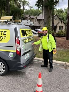 A CSIA-Certified Dryer Vent Specialist in a yellow safety helmet standing next to a branded Complete Dryer Vent Services van in front of a residential home.