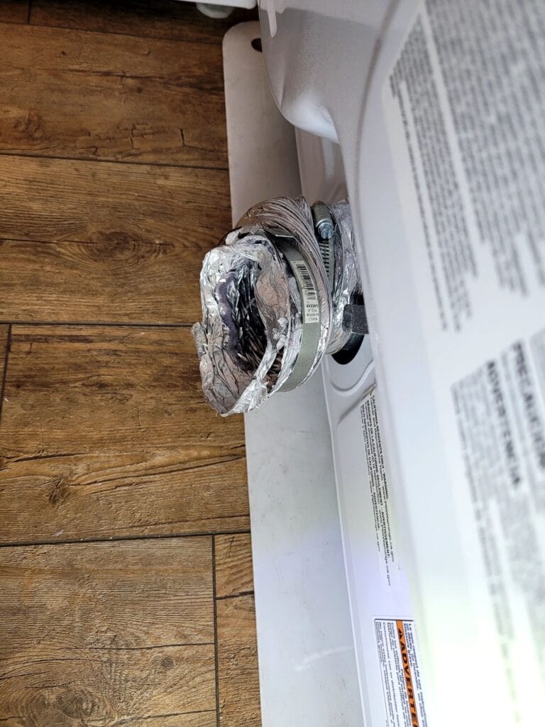 technician inspecting dryer vent duct for dryer burn residue with a flashlight