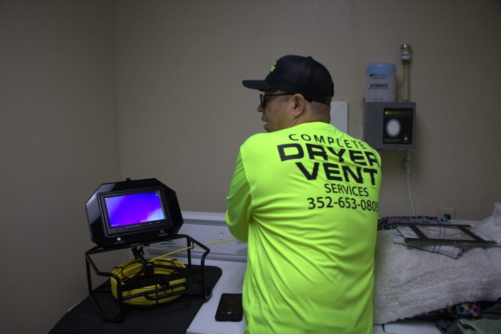 technician inspecting dryer vent for dryer overheating burning smell causes